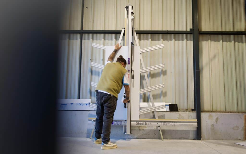 Keencut SteelTrak : Coupe-Panneaux Vertical Industriel Homme utilisant un coupe-panneaux vertical Keencut SteelTrak 210cm-82" pour la découpe précise de matériaux rigides.