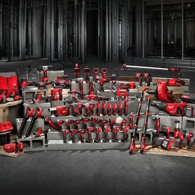Large collection d'outils électroportatifs rouges Milwaukee disposés sur un chantier avec des structures métalliques.