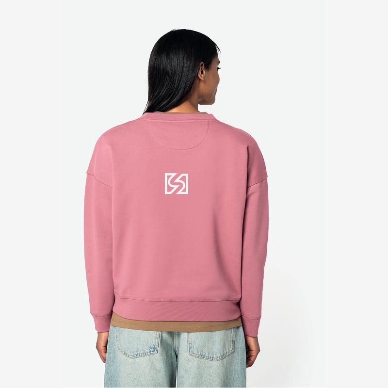 Sweatshirt oversize rose mauve femme – Vue de dos avec logo Dos d'une femme portant un sweatshirt oversize rose mauve. Petit logo blanc stylisé 'S' encadré au centre du dos, sur un jean large clair.