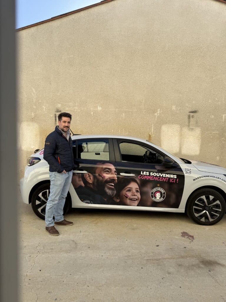 Centurions Narbonne Volley : Promotion et Voiture Floquée Homme souriant devant une voiture floquée Centurions Narbonne Volley : Les souvenirs commencent ici !