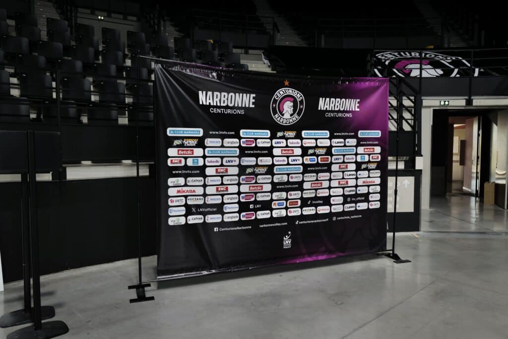 Narbonne Centurions : Bannière Interview Volleyball Bannière d'interview Narbonne Centurions Marmara Spike Ligue avec logos sponsors dans un stade de volleyball.