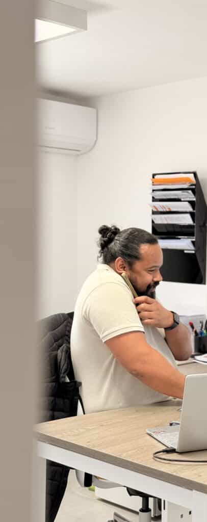Travail de bureau : homme au téléphone avec ordinateur Homme avec chignon travaillant sur son ordinateur portable tout en téléphonant dans un bureau moderne.