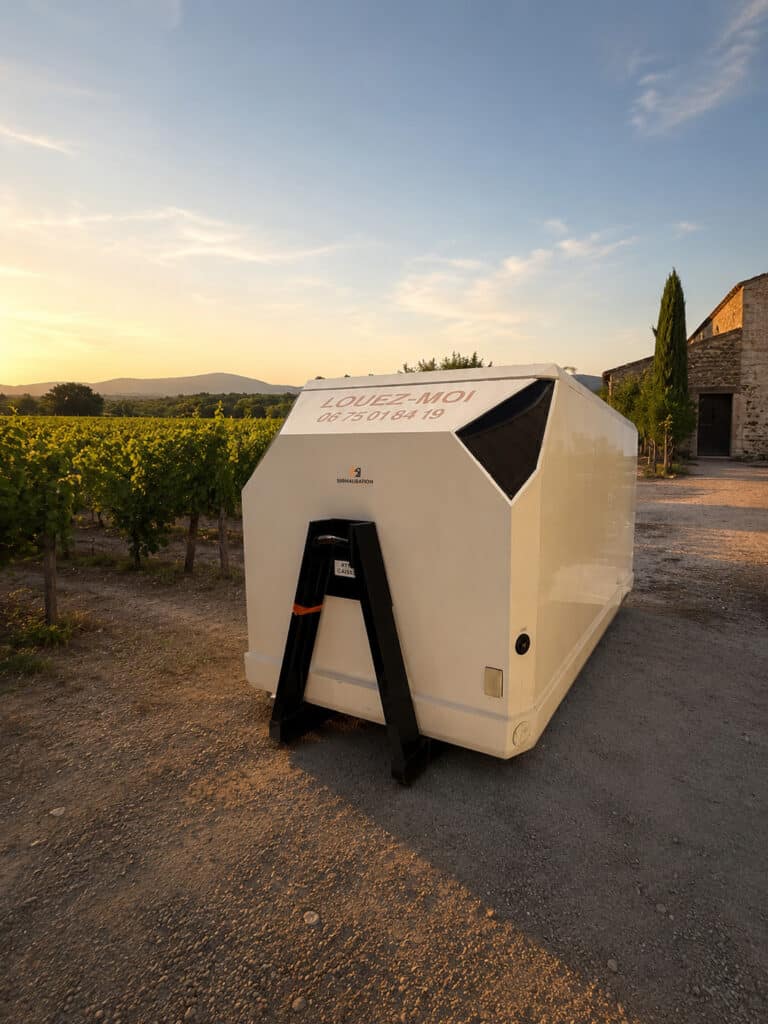 Location Cabine de Signalisation Moderne en Vignoble Cabine blanche "LOUEZ-MOI" Signalisation au cœur d'un vignoble au coucher du soleil. Design moderne et futuriste.